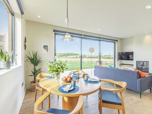 Un espace repas moderne avec une table ronde, des chaises et une vue sur l’extérieur.