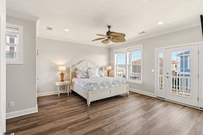 A bedroom with a bed, a ceiling fan, and a view of the outside.