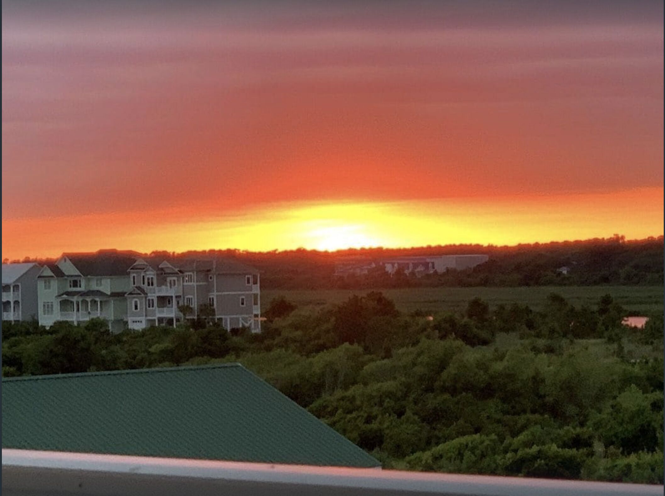 A residential area with houses and a green field during sunset.