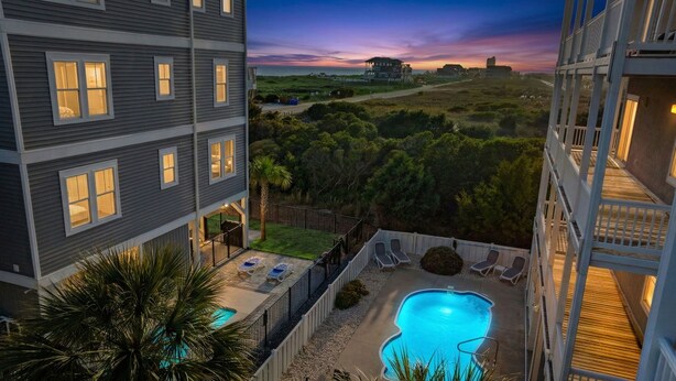 A multi-story hotel with a swimming pool, outdoor seating, and a view of the ocean at sunset. - Papa’s Porch, 8BR Beach House, Private Pool, Elevator, Sleeps 20 (Ocean Isle Beach)