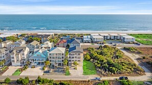 A coastal residential area with beachfront properties, including houses with balconies and a road leading to the beach.
