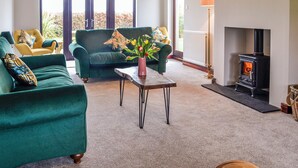 A living room with a sofa, armchairs, a coffee table, and a fireplace. - 4 bedroom accommodation in Carlisle (Carlisle)