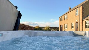 A hot tub in a residential setting with a brick house in the background. - 4 bedroom accommodation in Carlisle (Carlisle)