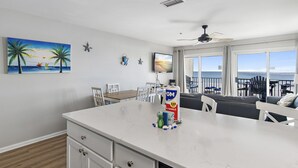 A modern kitchen with a large island, white cabinetry, and a view of the ocean. - Windancer 212. Gulf Front End Unit, Free Beach Service, Heated Pool. (Miramar Beach)