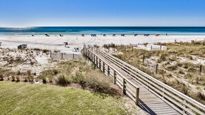 A beach with a wooden boardwalk leading to the shore, sandy beach, and clear blue sky. - Windancer 212. Gulf Front End Unit, Free Beach Service, Heated Pool. (Miramar Beach)
