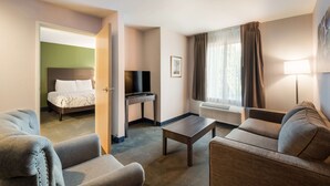 A hotel room with a bed, a TV, a desk, a coffee table, and two sofas.
