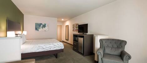 A hotel room with a bed, a desk, a chair, a television, and a cabinet.