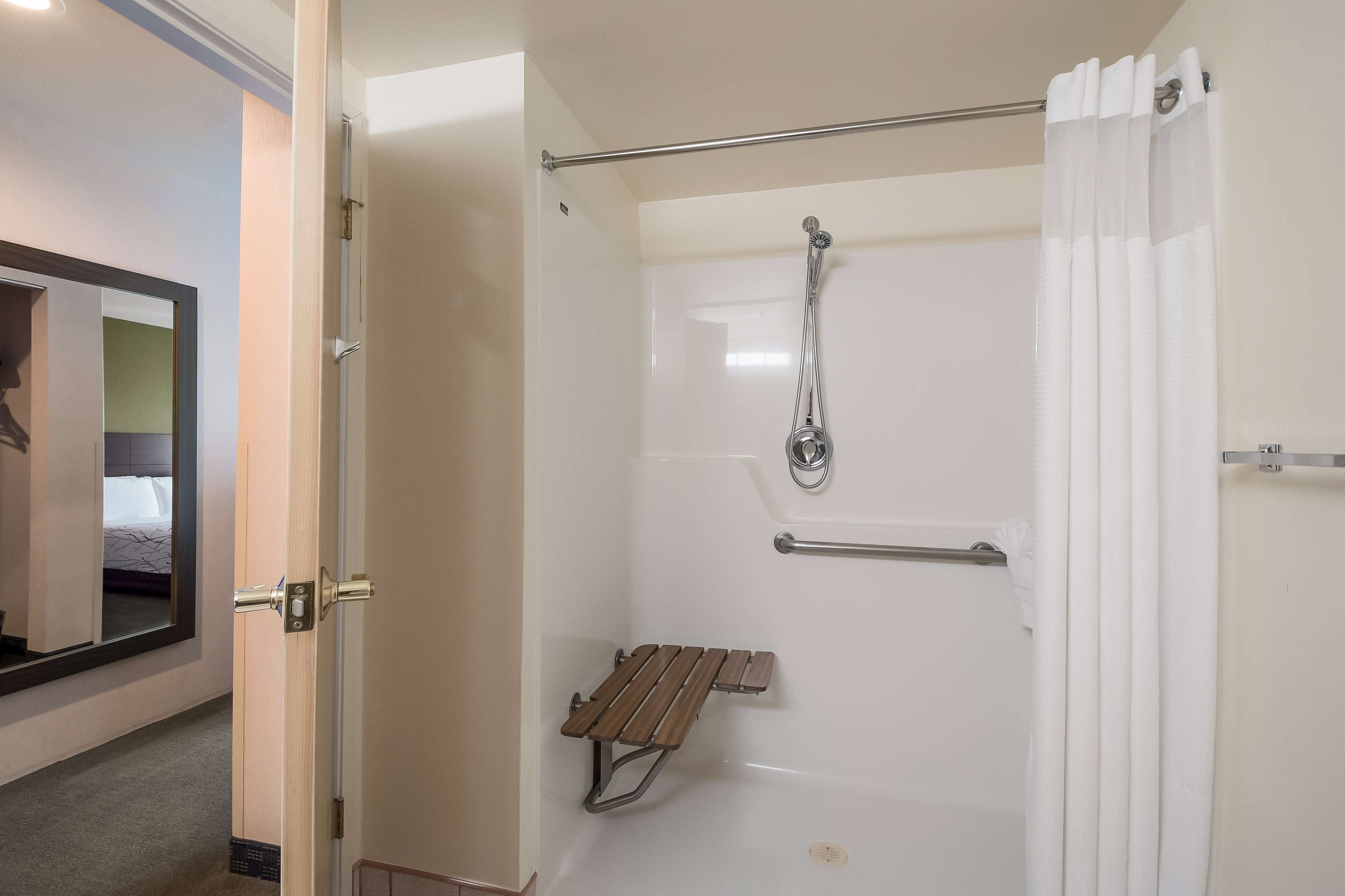 A shower with a bench, a towel rack, and a shower curtain.