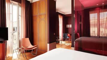 A hotel room with a bed, a TV, a wooden wardrobe, a chair, and a small table.