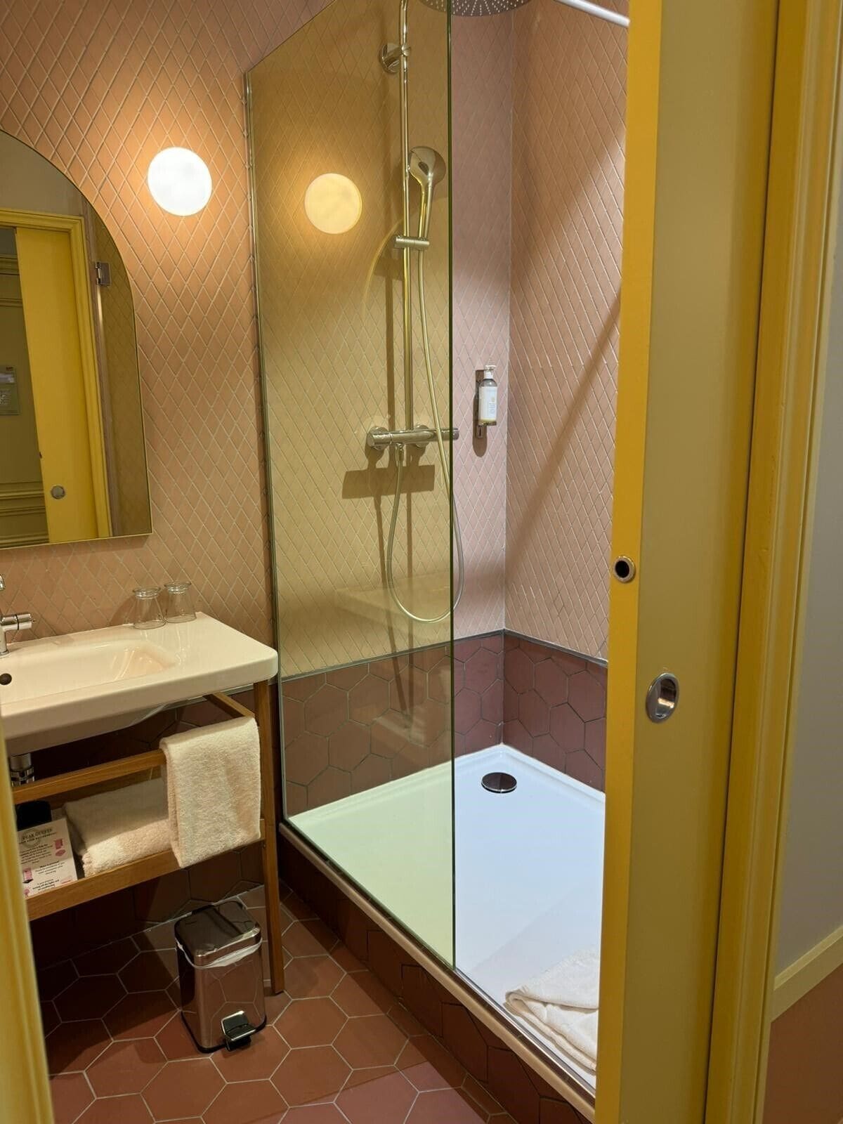 A modern bathroom with a glass-enclosed shower, a sink with a mirror, and a towel rack.