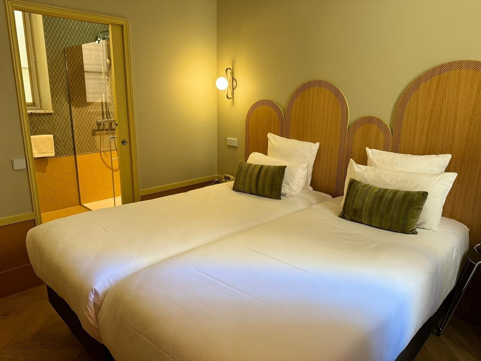 A hotel room with a large bed, a shower area, and a mirror.