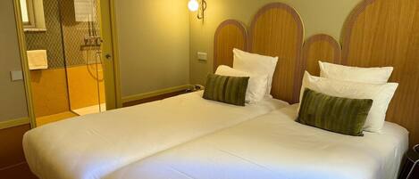 A hotel room with a large bed, a shower area, and a mirror.