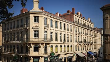 Un edificio histórico con varios pisos, ventanas grandes y una entrada destacada en esquina.