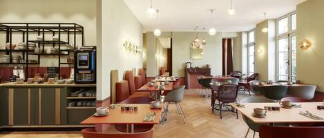 A modern cafe with wooden flooring, red and black chairs, and a variety of seating arrangements.