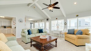 A spacious living room with a wooden coffee table, two sofas, and a ceiling fan. - 2nd Row Gulf View Home w/ 2 Decks, Board Games, 3 Kings+Bunk all w/Deck Access (Galveston)