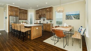 Una cocina amplia con armarios de madera, una isla central con taburetes y una zona de comedor con banco.