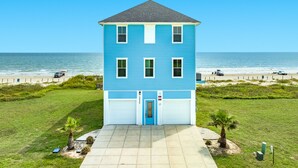Un edificio de dos pisos con fachada azul, una puerta principal y un garaje.