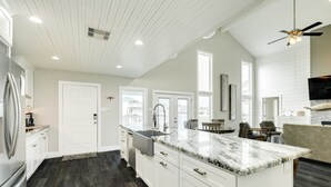 A spacious kitchen with white cabinetry, a marble countertop, and a dark wood floor. - Private Canal Home w/ 2 Living Areas, Easy Bay Access & POOL (Galveston)