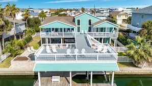 A waterfront property with a two-story building, a dock, and a pool area. - Private Canal Home w/ 2 Living Areas, Easy Bay Access & POOL (Galveston)