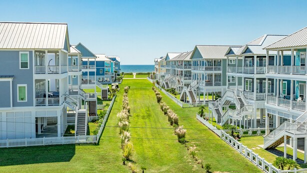 A beachfront hotel with multiple-story buildings, balconies, and a central lawn. - Beachside Home w/ POOL, 2 Covered Decks - 2 Blocks to Beach, 9 mi from Downtown (Galveston)