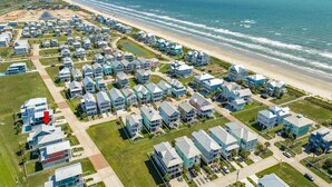 An aerial view of a coastal residential area with houses and a beach. - Luxurious Beachside Home - All Suites, Large Living/Dining, Screened Porch (Galveston)