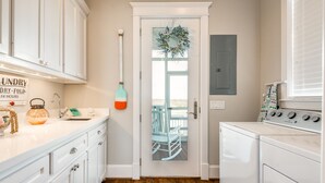 A kitchen with white cabinets, a wooden floor, a stove, and a door with a glass panel. - Luxurious Beachside Home - All Suites, Large Living/Dining, Screened Porch (Galveston)