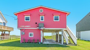 A pink building with a covered porch and a staircase leading to a deck. - Updated Pet Friendly Beachfront Home w/ Open Plan, Equipped Kitchen, Free Wifi (Galveston)