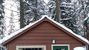 Une petite cabane avec une porte verte, deux chaises à l’extérieur et le chiffre « 3 » peint sur le mur.