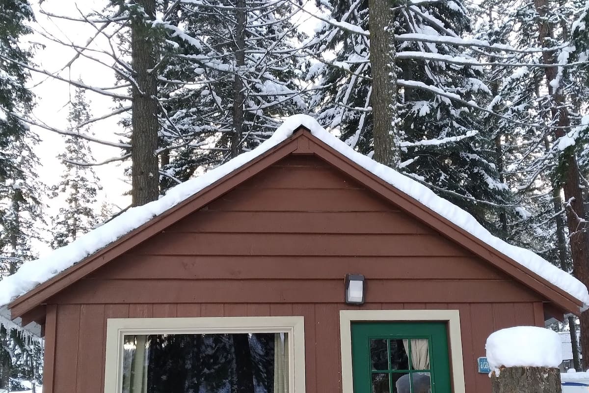 Uma cabana pequena com uma porta verde, duas cadeiras do lado de fora e o número 3 na parede.