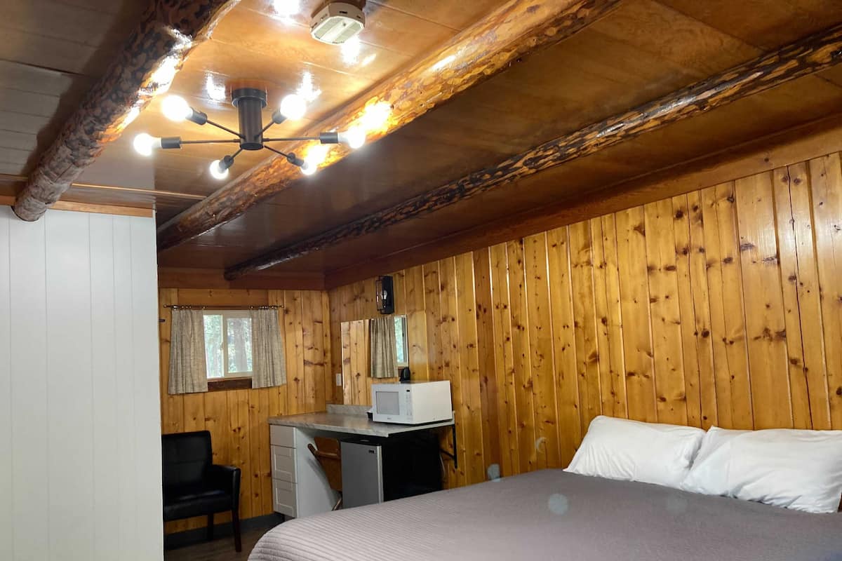 Quarto de cabana de madeira com uma cama, uma escrivaninha e uma cadeira.