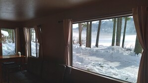 Une pièce chaleureuse avec une grande fenêtre donnant sur une forêt enneigée.