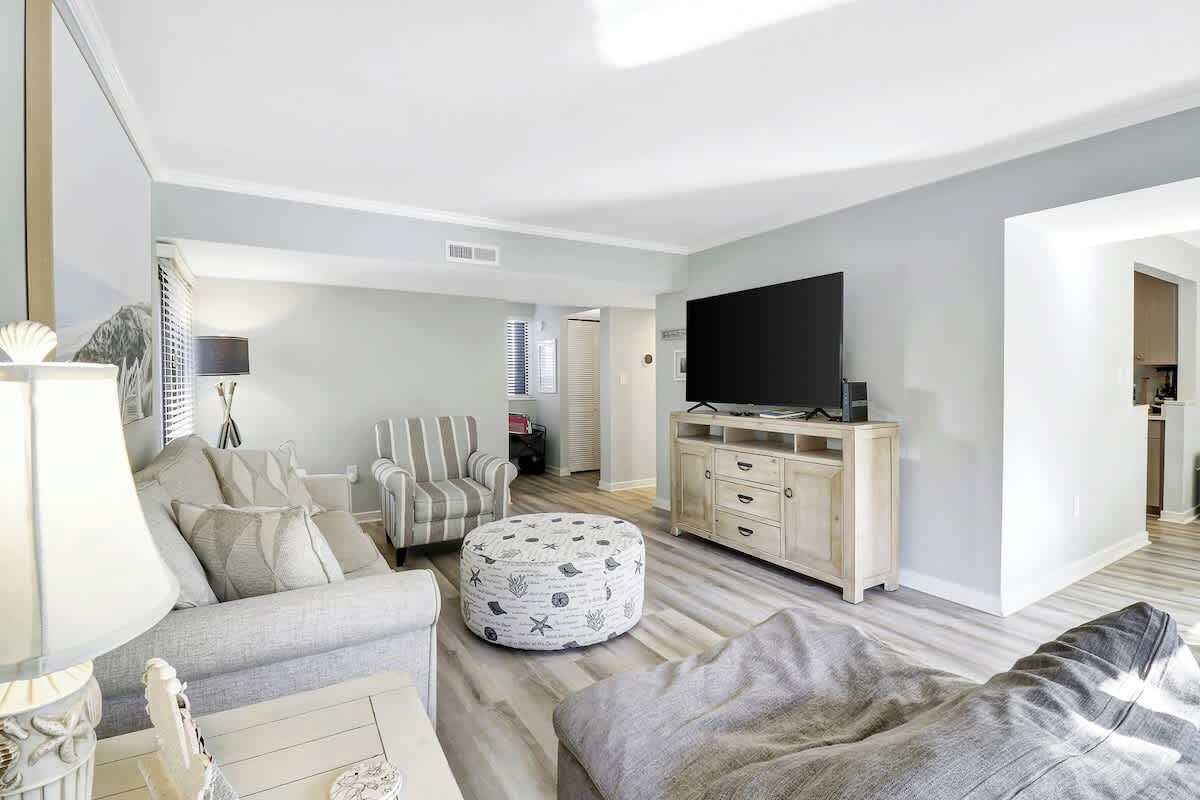 A modern living room with a sofa, ottoman, and a flat-screen TV on a wooden cabinet.