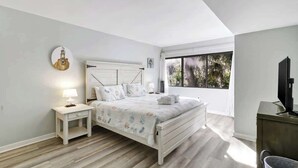 A bedroom with a bed, nightstand, and a television. - Poolside Beach Villa 2 bed 2 & one half bath-Pet Friendly (Hilton Head Island)
