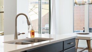 A modern kitchen with a stainless steel sink, a bottle of hand soap, and a window with a view of a building. - LeBlanc 5 Bedroom!  5 Bath! Firepit! Dog Friendly! (Washington)