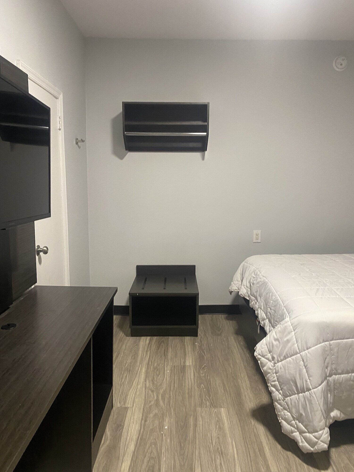 Une chambre à coucher avec un lit, une télévision, une étagère et une porte.