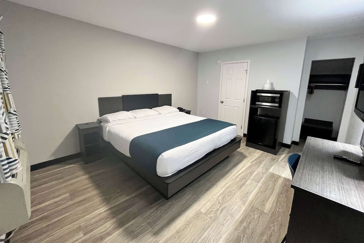 A hotel room with a bed, a desk, a television, and a door.