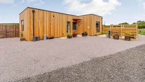 A modern wooden building with a gravel driveway and a wooden fence in the background.