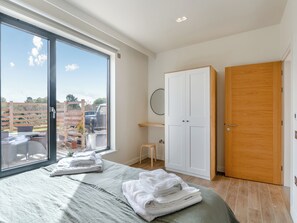 A bedroom with a large window, a bed, a wardrobe, and a small stool. - Buttercup Lodge - UK36655 (Boothby Pagnell)