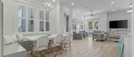 A spacious living area with a dining set, sofas, and a TV.
