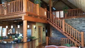 Un interior espacioso con una escalera de madera, una zona de cocina y un área de estar con sofás de cuero.