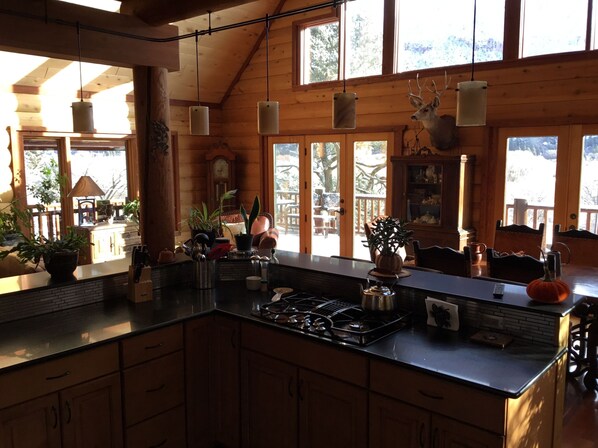 A spacious kitchen with wooden cabinets, a central island, and large windows.