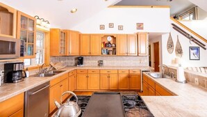 A modern kitchen with wooden cabinets, a gas stove, a kettle, and a coffee maker. - The Smitty Place- family friendly, near downtown, great parking! (McCall)