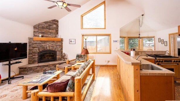A cozy living room with a stone fireplace, wooden furniture, and a kitchen area with a stove and sink. - The Smitty Place- family friendly, near downtown, great parking! (McCall)