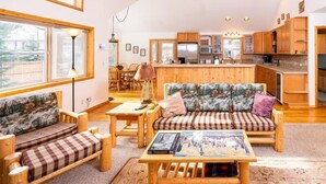 A cozy living room with wooden furniture, a sofa with floral cushions, and a coffee table with books. - The Smitty Place- family friendly, near downtown, great parking! (McCall)