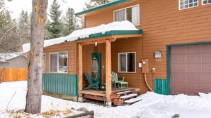 A wooden house with a porch, green chairs, and a garage door. - The Smitty Place- family friendly, near downtown, great parking! (McCall)