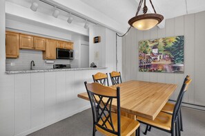A kitchen with white cabinets, a microwave, and a dining area with a wooden table and chairs.