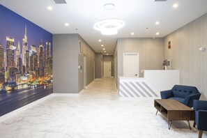 Un lobby de hotel con un mural de la ciudad, una recepción y un área de descanso.