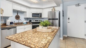 Une cuisine moderne avec des armoires blanches, des appareils en acier inoxydable et un comptoir en granit.