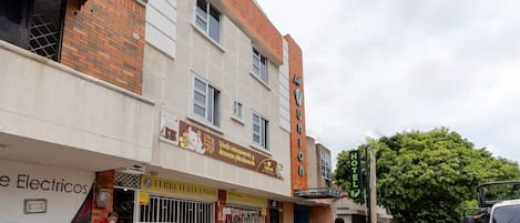 A hotel with a signboard, a storefront with a signboard, and a parked motorcycle.