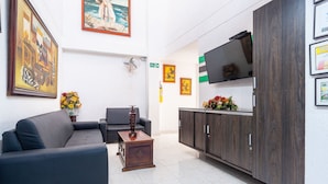 A modern lobby with a sofa, a small wooden table, a TV on a cabinet, and framed artwork on the walls. - Hotel Union (Valledupar)